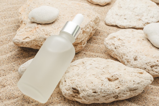 Moisturizing face serum on summer sea sandy surface with stones