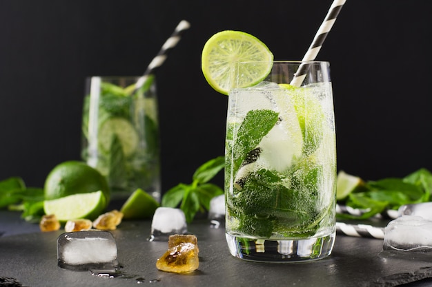 Mojito cocktail in glass on black table. Low key photo. Close up.