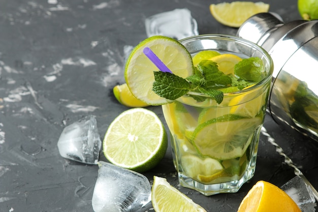 Mojito cocktail in a glass with lime, mint and lemon and bar accessories on a dark concrete background. make a mojito.