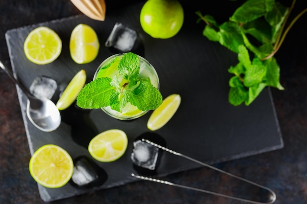 Photo mojito cocktail and ingredients on a dark background refreshing cocktail mojito on a slate board