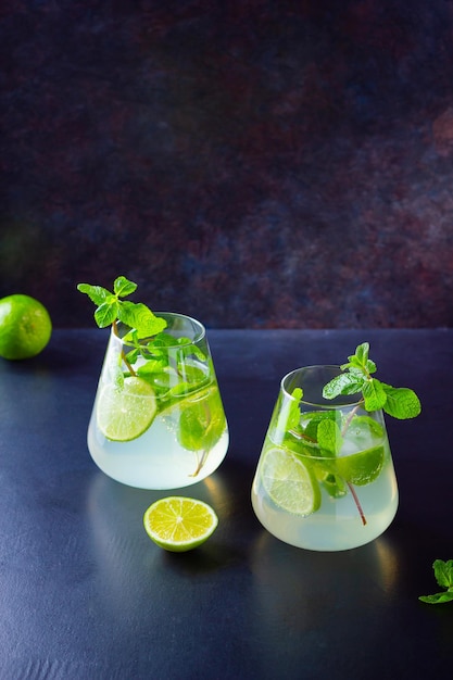 Mojito cocktail with lime and mint in glass Two glasses of mojito on a dark background