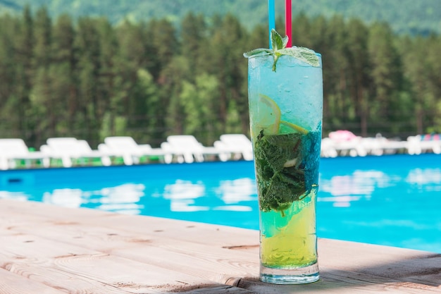 Mojito cocktail with lime and mint in highball glass at the swiming pool