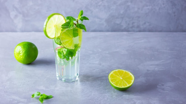 Mojito cocktail with lime and mint in tall glass Fresh mojito in glass on a gray background