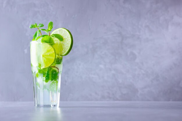 Mojito cocktail with lime and mint in tall glass Fresh mojito in glass on a gray background