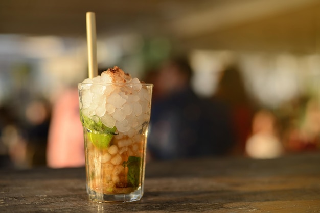 Mojito at sunset at a beach bar with people in the background out of focus.