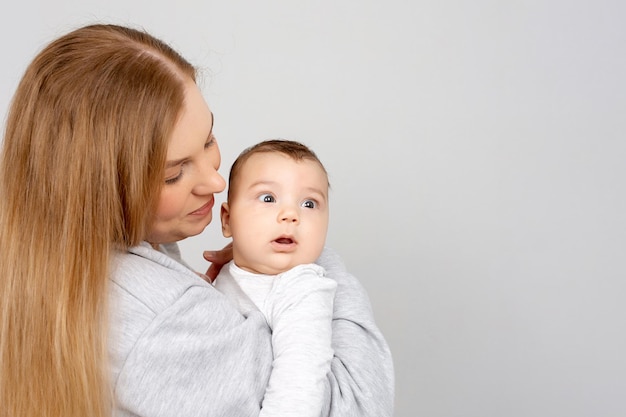 Mom and baby play on the bed Mother and son happy family beautiful blonde girl and cute baby at home