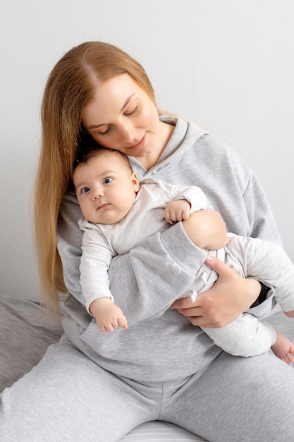 Mom and baby play on the bed Mother and son happy family beautiful blonde girl and cute baby at home