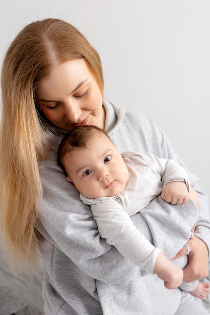 Mom and baby play on the bed Mother and son happy family beautiful blonde girl and cute baby at home