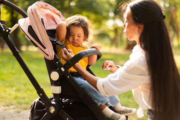 Mom caring for daughters comfort during walk in stroller outside