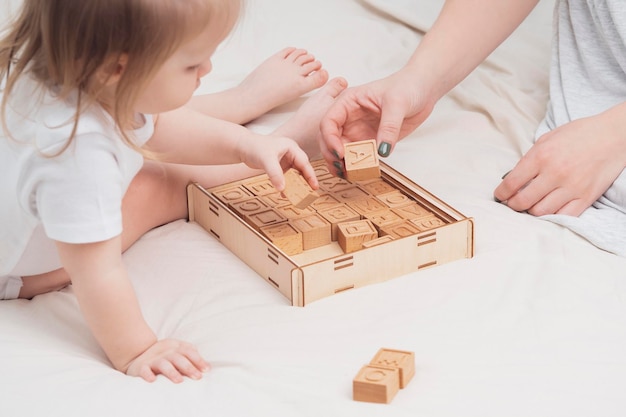 Mom and child are learning the English alphabet closeup The child plays with wooden cubes with English letters The concept of early development preschool education at home Educational games