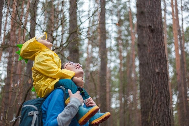 Mom and child walking in the forest after rain in raincoats together