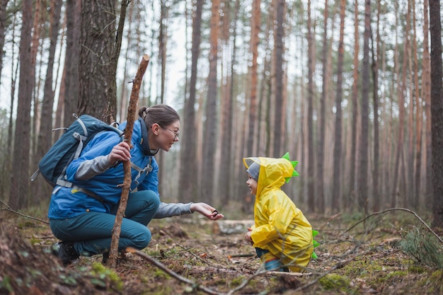 Mom and child walking in the forest after the rain in raincoats together