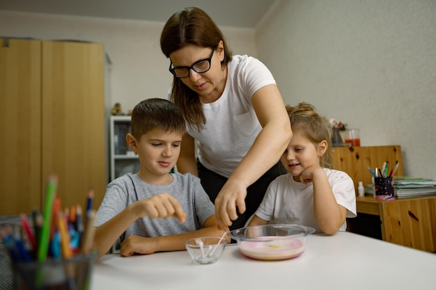 Mom and children are having fun at home experimenting with milk and paints