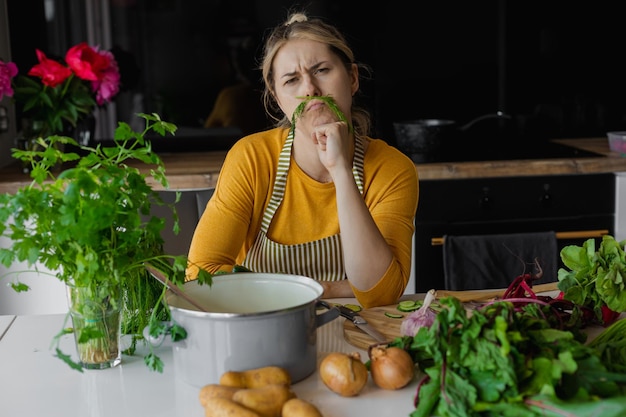 Mom cooking humor healthy food concept funny young woman using dill as mustache in kitchen vegetable