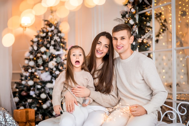 Mom, Dad and daughter at Christmas. Portrait of a family on a New Year's background