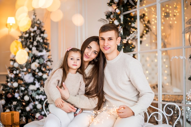 Mom, Dad and daughter at Christmas. Portrait of a family on a New Year's background