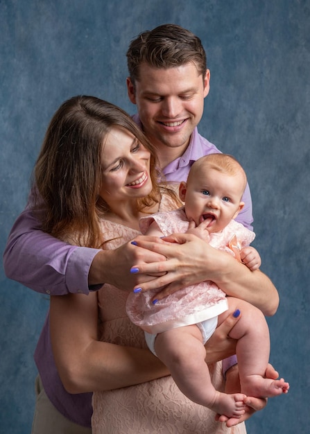 Mom and dad hold a little daughter in their arms and look tenderly at her Love of young parents