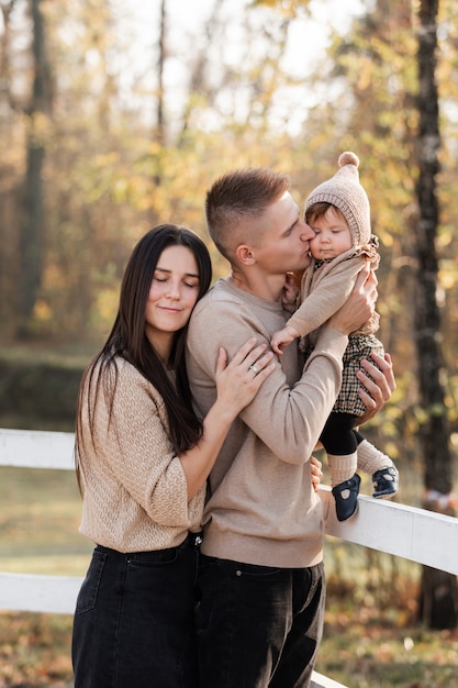 Mom and dad hugging daughter and kissing in the autumn park