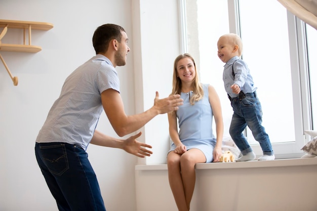 Mom dad and little son are playing at home Young family with a child