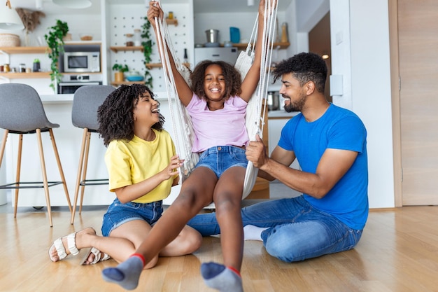 Mom and dad swinging and having fun with their daughter at home