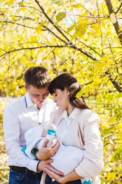 Mom and dad with a baby, a little boy walking in the fall in the Park or forest. Yellow leaves, the beauty of nature. Communication between a child and a parent.