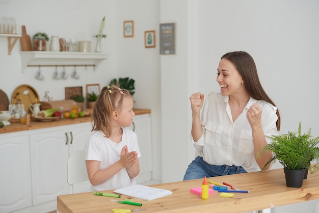 Mom and daughter are happy to finish their homework in the kitchen. Home life. Real joy.