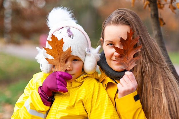 Mom and daughter are reading a book in the park Autumn place for text