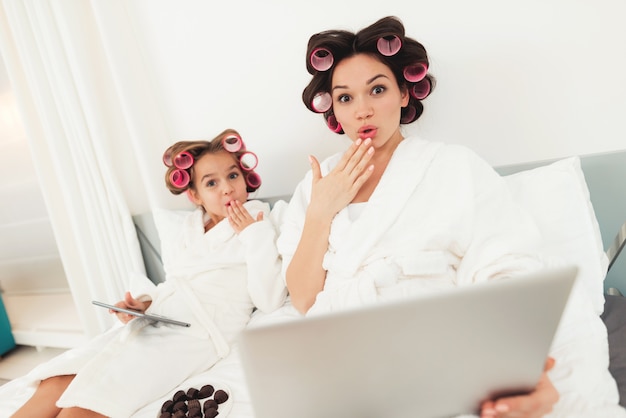 Mom and daughter in bed are watching something on laptop.