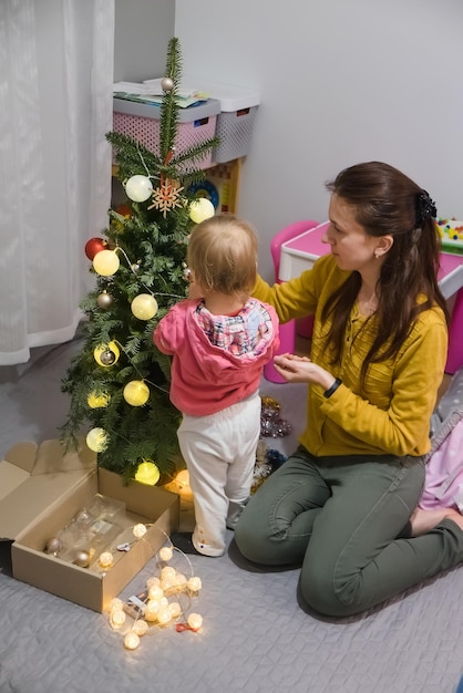 Mom and daughter decorate the christmas tree at home