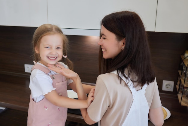 Mom and daughter fried pancakes together in the kitchen in a bright interior moms assistant and brea