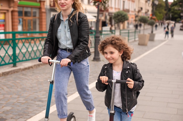 The mom and daughter have fun riding scooters