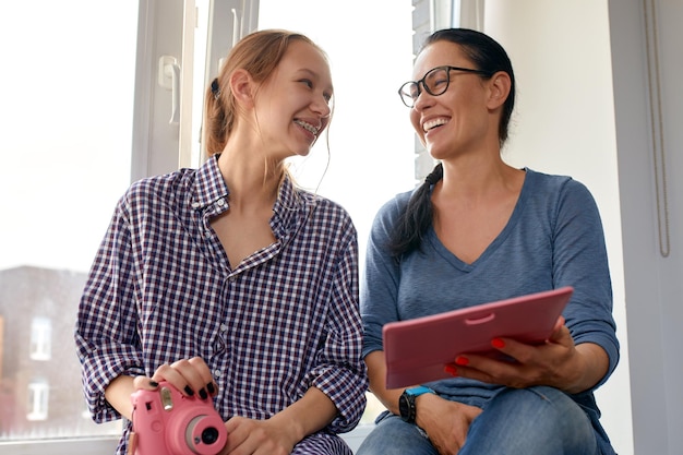 Mom and daughter look at a photo album at home and have fun