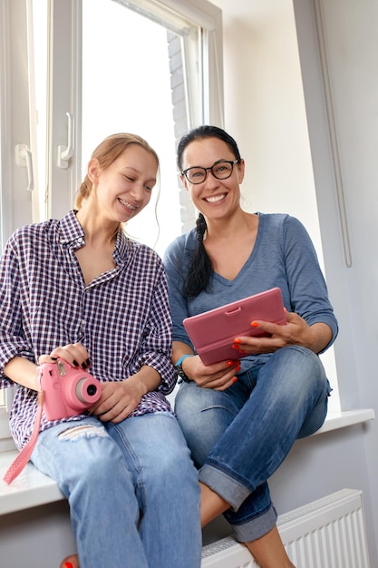 Mom and daughter look at a photo album at home and have fun