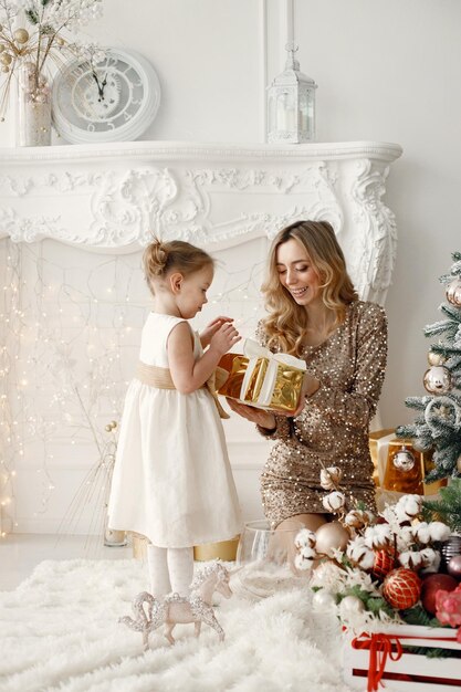 Mom and daughter opening a gift near Christmas tree together