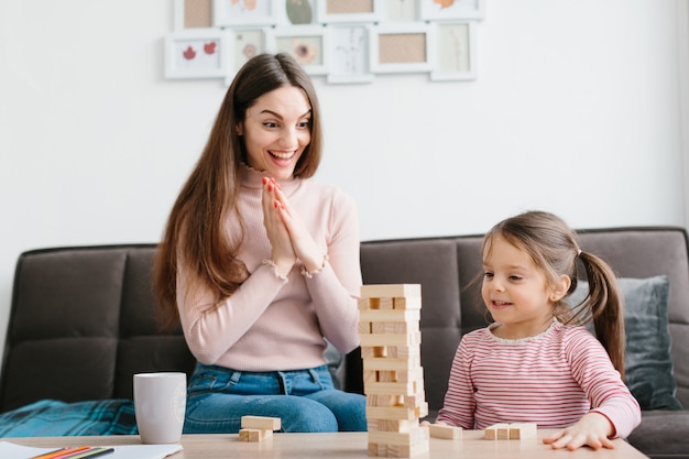 Mom and daughter play a board game in the living room.