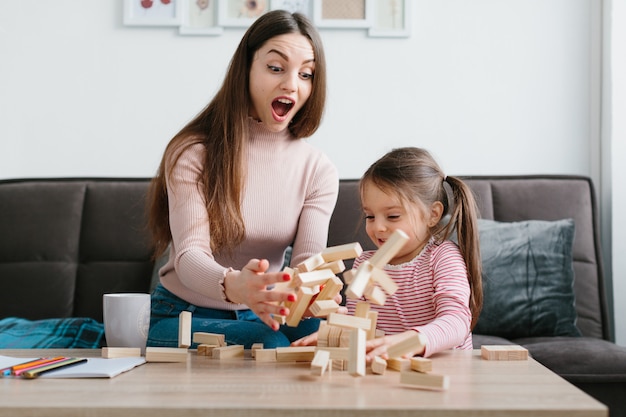 Mom and daughter play a board game in the living room.