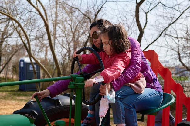 Photo mom and daughter pretending to ride a tractor at the county fair