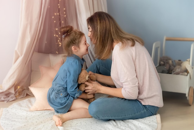 Mom and daughter tenderly hug and play merrily in the childrens room Photo in pink