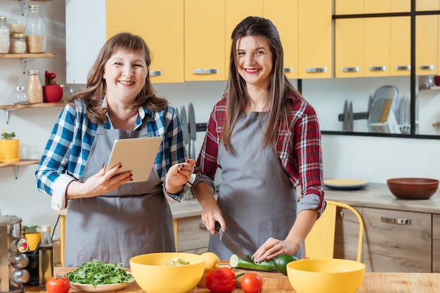 Mom and daughter using tablet when cooking in kitchen