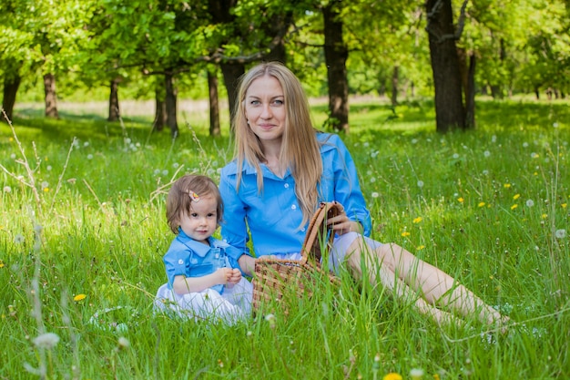 Mom and daughter walk in the woods in the same clothes and headbands. Picnic