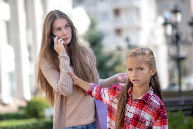 Mom and daughter walking along the street with shopping bags