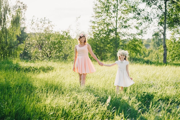 Mom and daughter walking on the field in the summer Sunny day at sunset