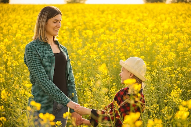 Mom and daughter on yellow bloomed rapeseed field