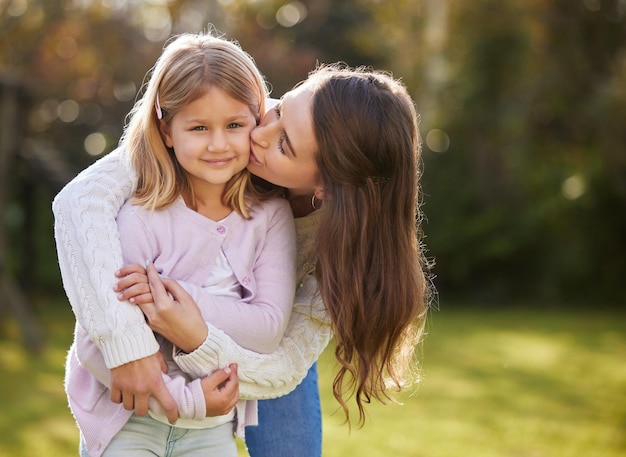 Mom girl and kiss in outdoor for love or family care holiday with trust in London garden Mother child and growth support with happiness or hug on vacation travel bokeh or mothers day in park