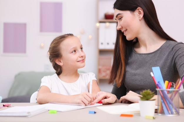 Mom helps the girl to do homework children and parents