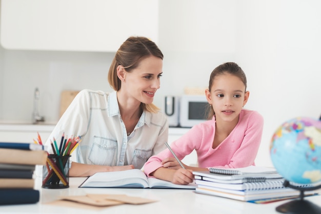 Mom helps my daughter do her homework in the kitchen 