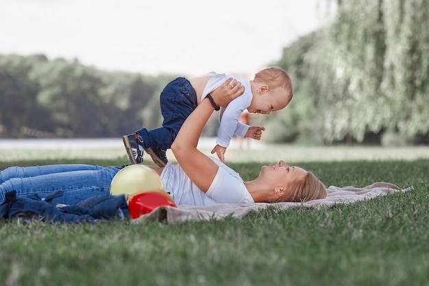 Mom and her little son playing lying on the lawn