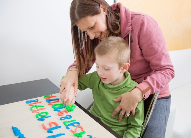 a mom and her young boy play with colored modeling clay