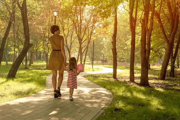 Mom holds the hand of a little girl with a balloon in the park Closeup handshake Happy family mom daughter