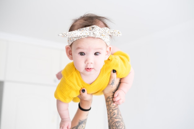 mom holds a healthy asian girl 5 months old in a yellow bodysuit